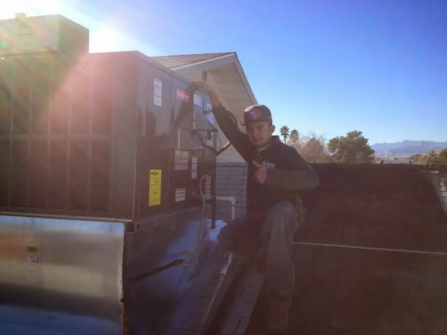 HVAC technician performing Boiler Repair on a rooftop unit in Buxton